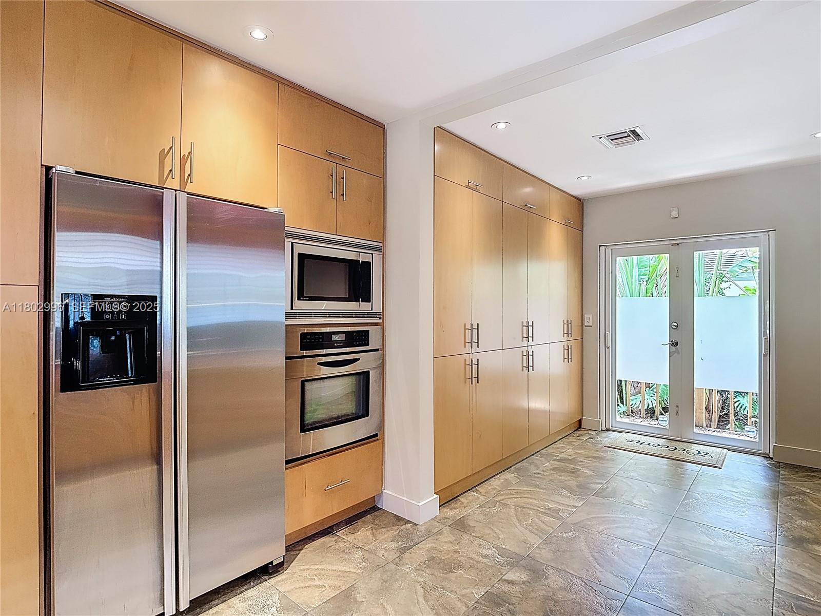 2810 Crystal Court Miami, FL 33133 - Photo 7 of 14 a kitchen with stainless steel appliances kitchen island a refrigerator and a sink