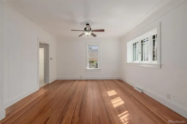 a view of empty room with wooden floor and fan