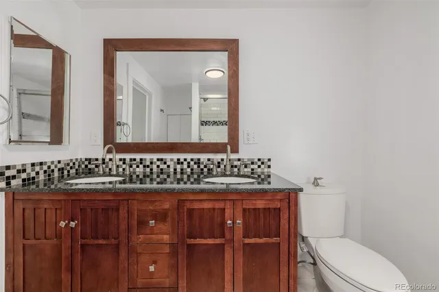 a bathroom with a granite countertop toilet sink and mirror