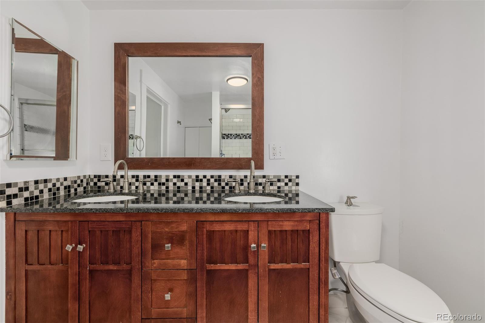 3534 Clay Street Denver, CO 80211 - Photo 21 of 50 a bathroom with a granite countertop toilet sink and mirror