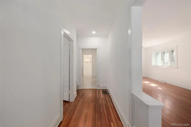 a view of a hallway with wooden floor and a bathroom