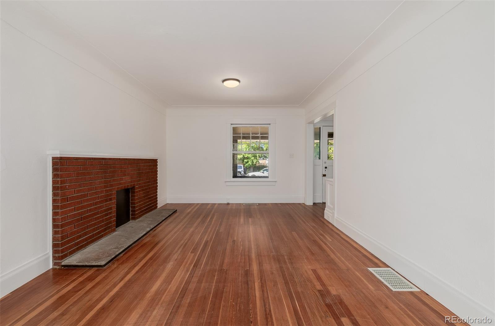 3534 Clay Street Denver, CO 80211 - Photo 10 of 50 an empty room with wooden floor fireplace and windows