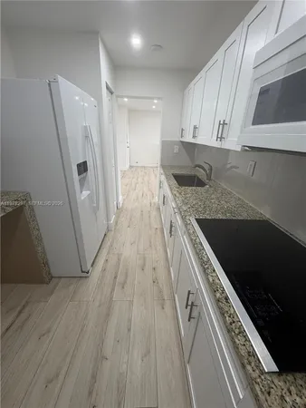 a kitchen with a sink a refrigerator and cabinets