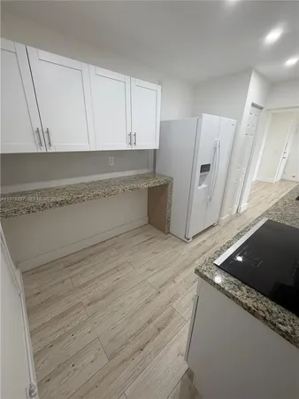 a kitchen with granite countertop a sink and a refrigerator