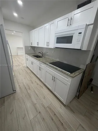 a kitchen with granite countertop white cabinets and white appliances