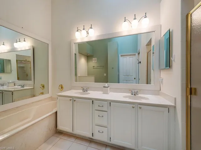 a spacious bathroom with a double vanity sink mirror and bathtub