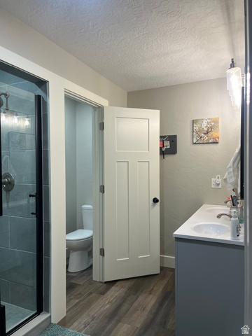 558 North N Cres Road Roosevelt, UT 84066 - Photo 11 of 31 Bathroom featuring a glass-enclosed shower with subway tile surround, a double vanity with white countertops, and wood-finish flooring