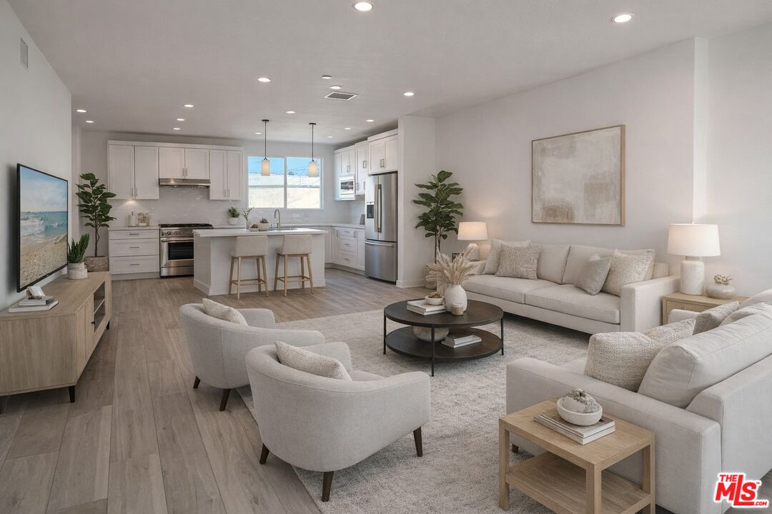 a living room with furniture kitchen view and a flat screen tv