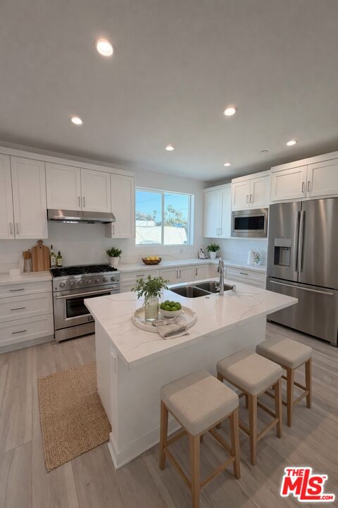 121 East 223rd Street, Unit 4 Carson, CA 90745 - Photo 2 of 14 a kitchen with stainless steel appliances granite countertop a stove a sink a microwave a refrigerator and white cabinets with wooden floor