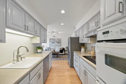 a kitchen with kitchen island granite countertop lots of counter top space a sink wooden cabinets and stainless steel appliances