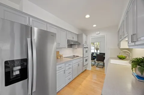 a kitchen with stainless steel appliances kitchen island granite countertop a refrigerator a stove and a sink