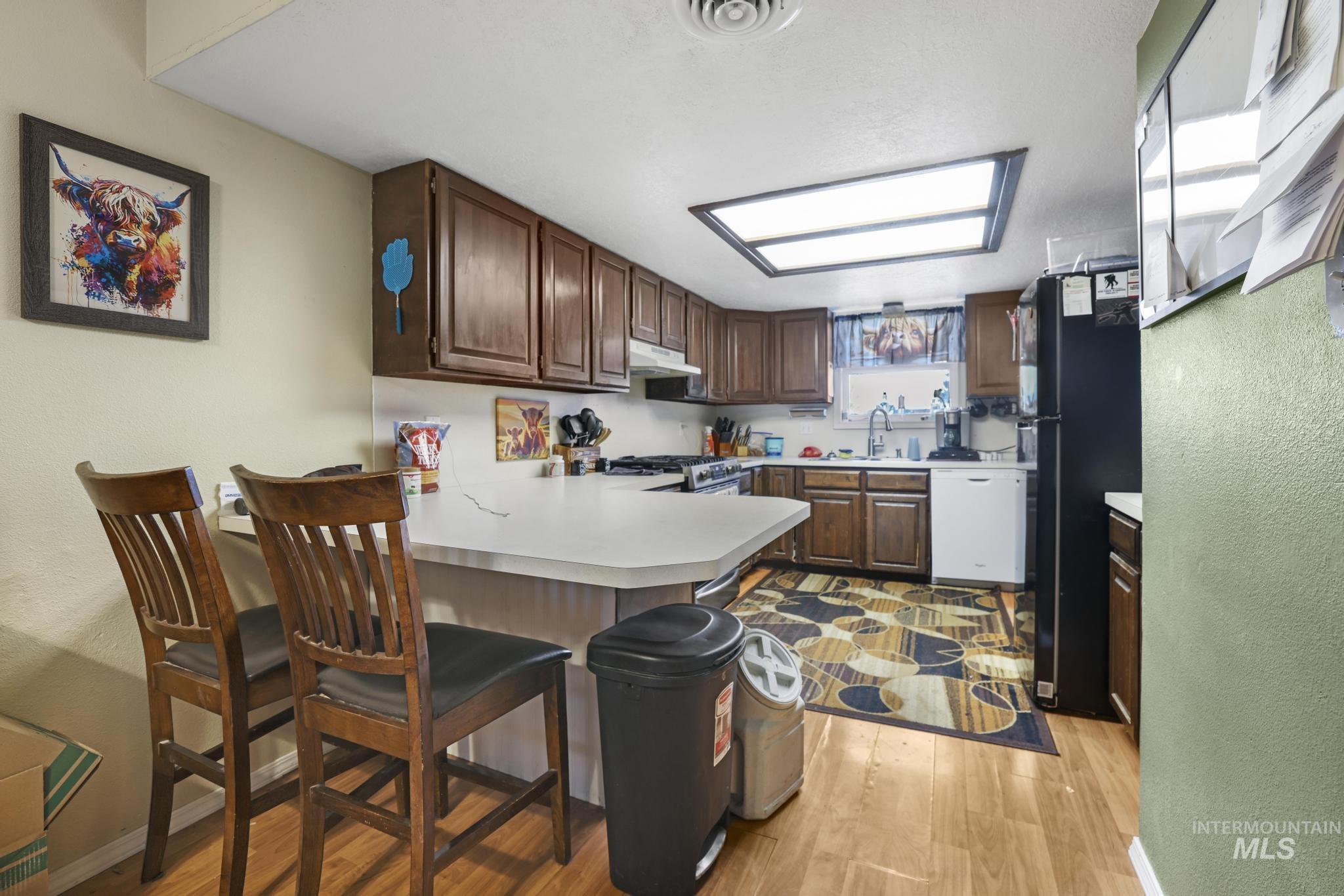 721 Beta Circle Twin Falls, ID 83301 - Photo 12 of 28 Kitchen featuring a textured wall, light countertops, a peninsula, freestanding refrigerator, and white dishwasher
