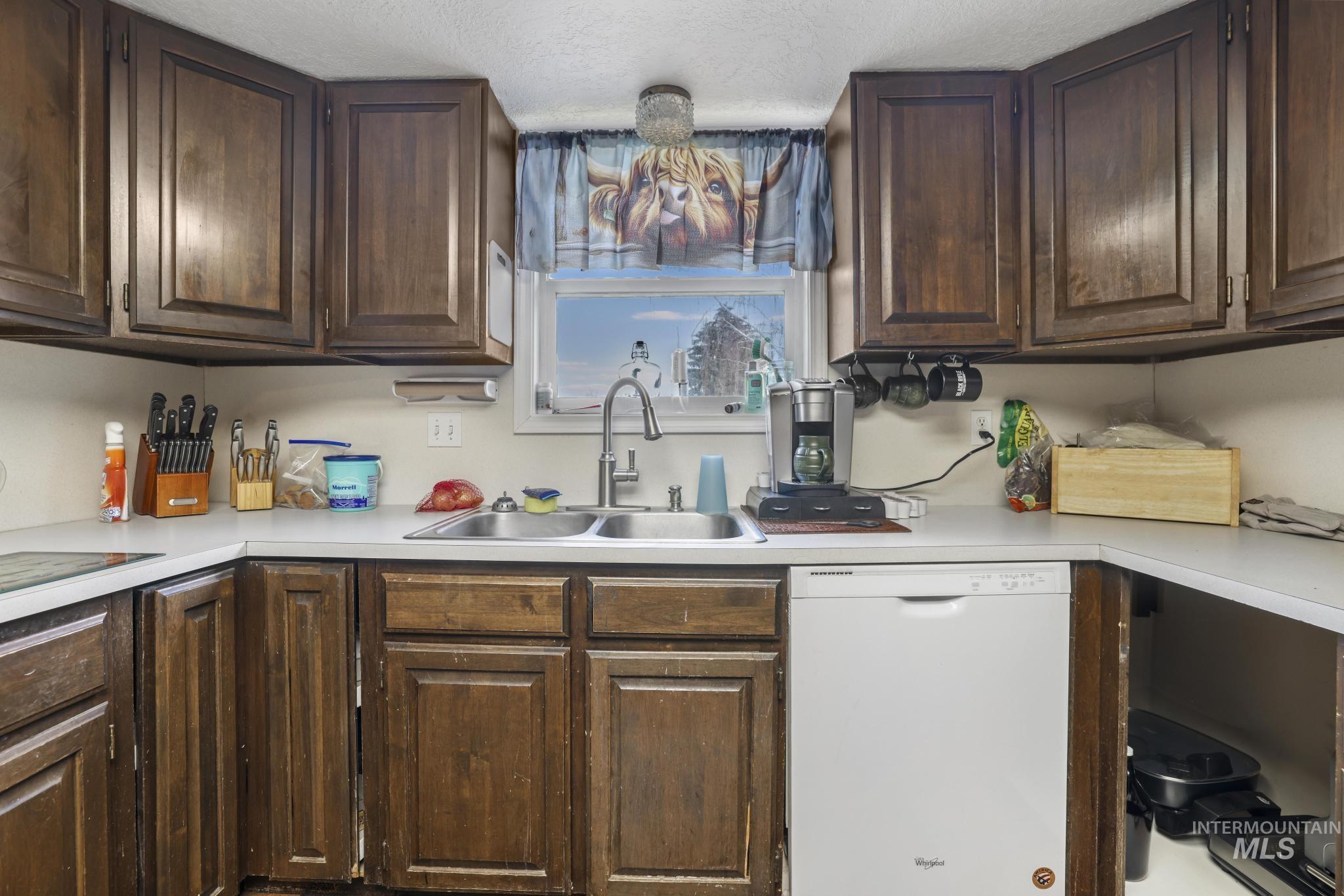 721 Beta Circle Twin Falls, ID 83301 - Photo 14 of 28 Kitchen featuring dark brown cabinetry, white dishwasher, light countertops, and a chandelier