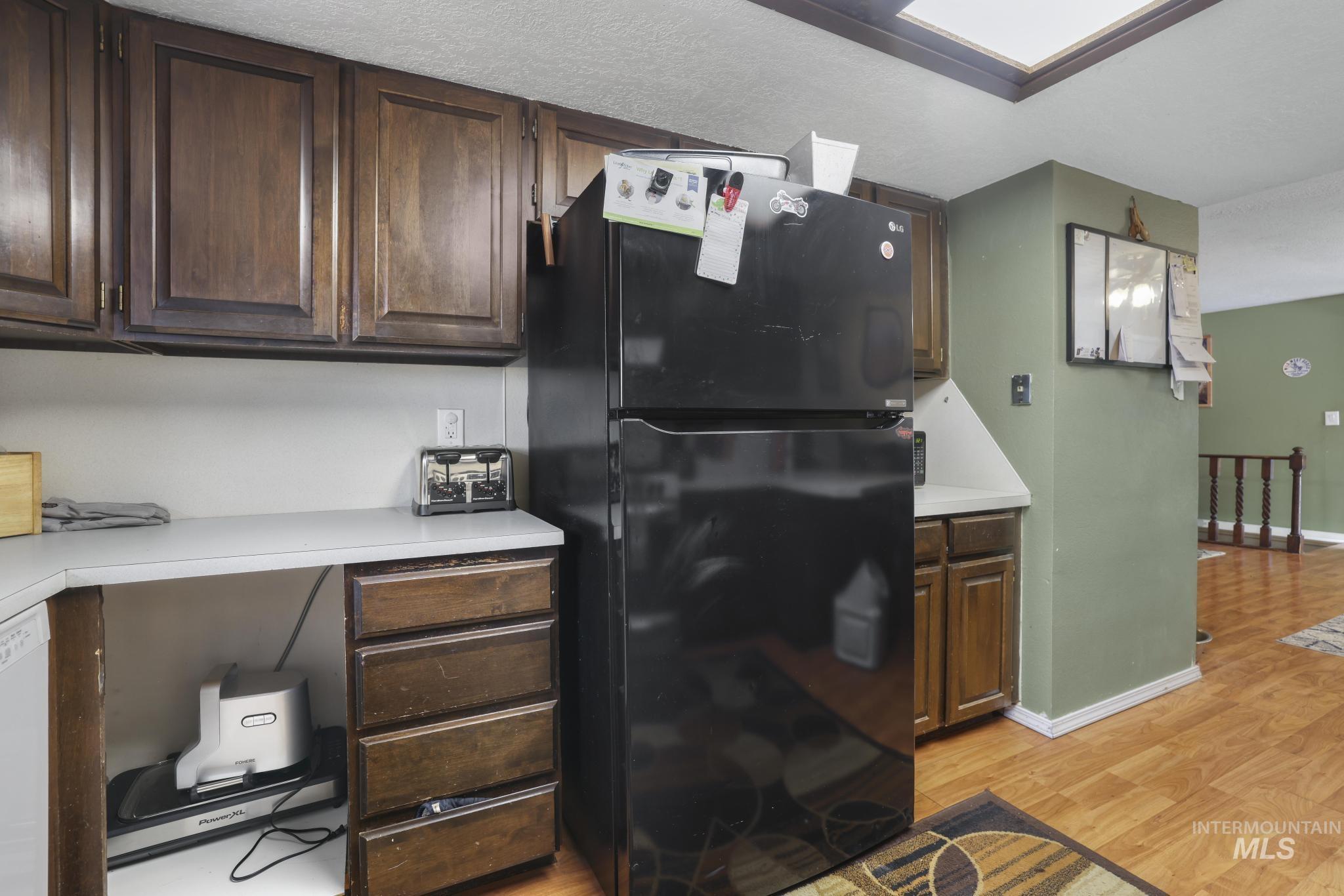 721 Beta Circle Twin Falls, ID 83301 - Photo 16 of 28 Kitchen featuring freestanding refrigerator, light countertops, light wood-style floors, and dark brown cabinets