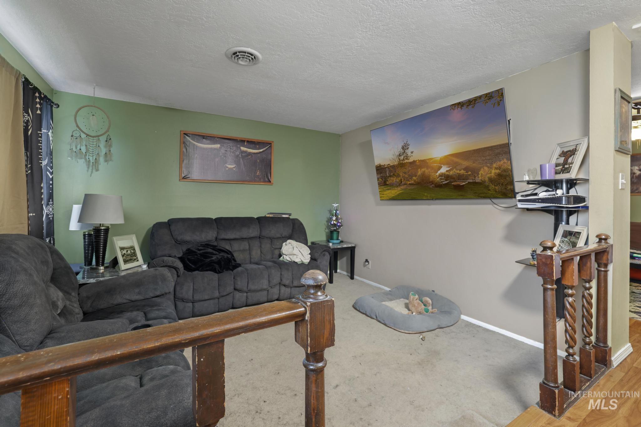 721 Beta Circle Twin Falls, ID 83301 - Photo 7 of 28 Carpeted living room with a textured ceiling and baseboards