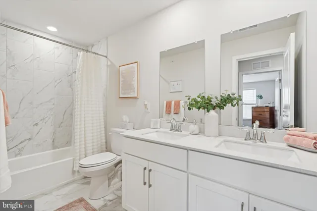a bathroom with a granite countertop sink a toilet and shower