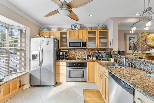 a kitchen with stainless steel appliances granite countertop a refrigerator a stove and a sink