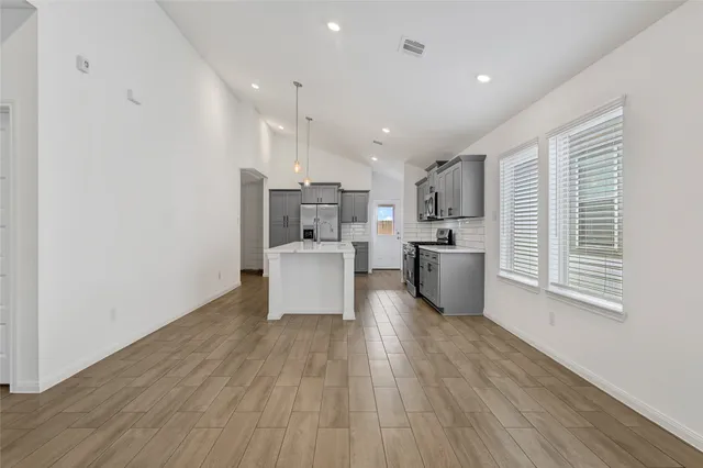 a kitchen with stainless steel appliances a refrigerator and a wooden floor