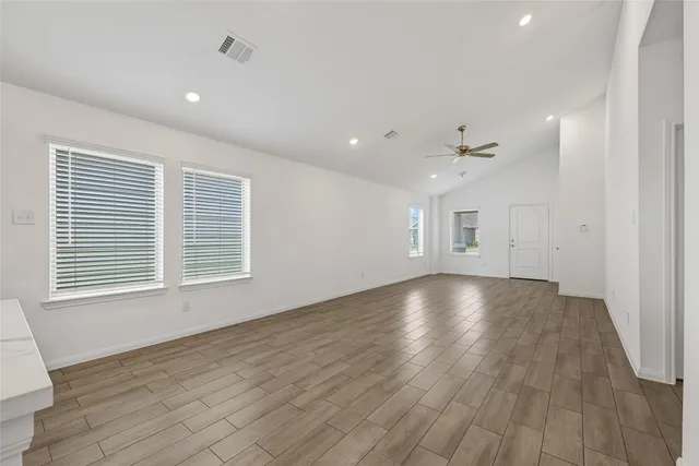 a view of an empty room with wooden floor and a window