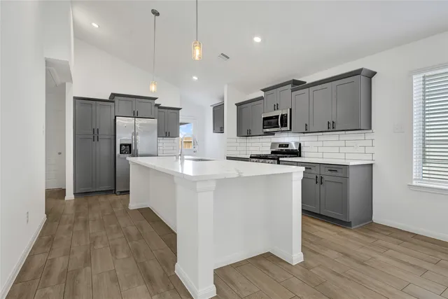 a kitchen with kitchen island granite countertop a sink cabinets and stainless steel appliances