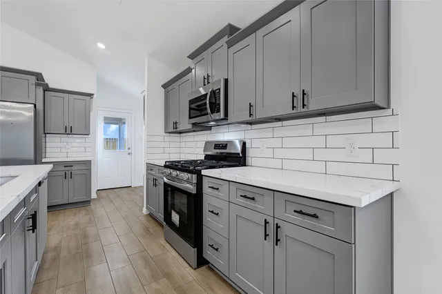 a kitchen with stainless steel appliances white cabinets a sink and a stove