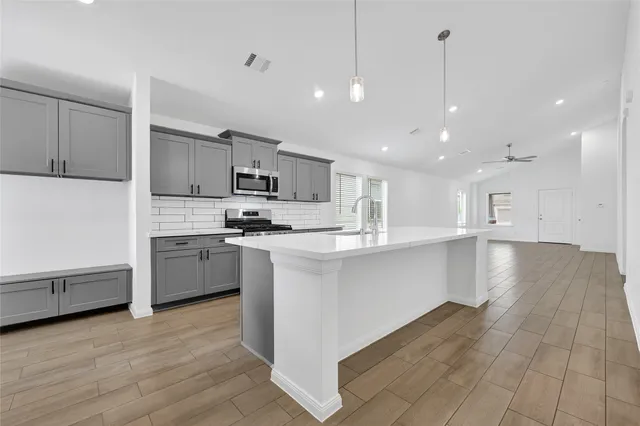 a kitchen with stainless steel appliances kitchen island granite countertop a stove a sink and a refrigerator