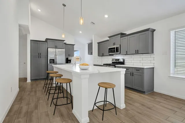 a kitchen with stainless steel appliances a dining table chairs refrigerator and microwave
