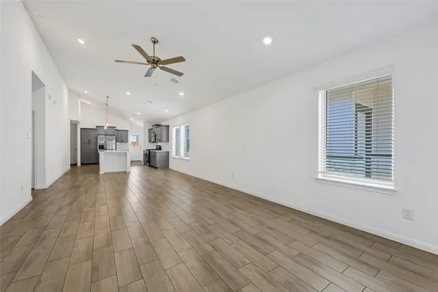 a view of a electric appliances in kitchen and empty room with wooden floor