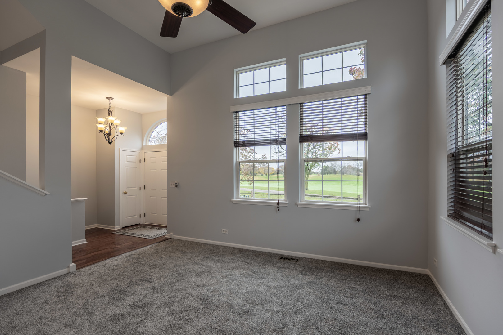 2430 Courtyard Circle, Unit 6 Aurora, IL 60506 - Photo 4 of 28 an empty room with chandelier fan and windows