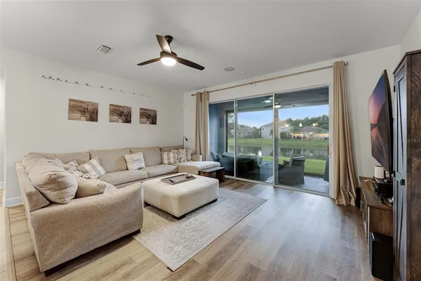 a living room with furniture floor to ceiling window and wooden floor