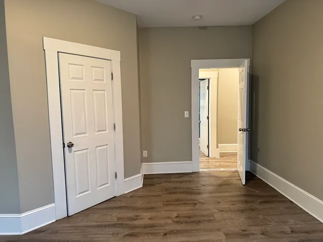 an empty room with wooden floor and closet area