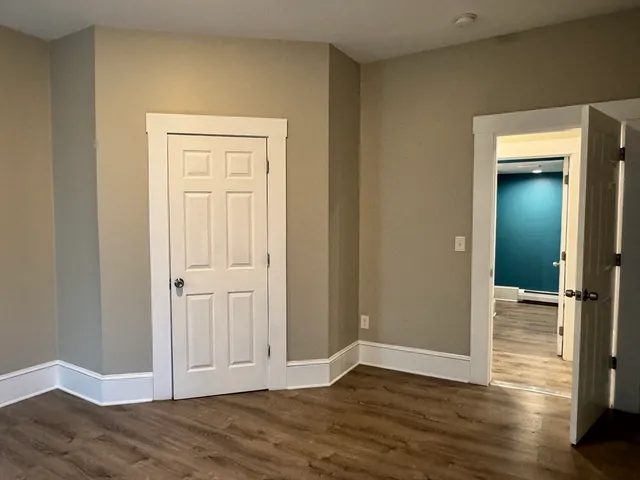an empty room with wooden floor & closet area