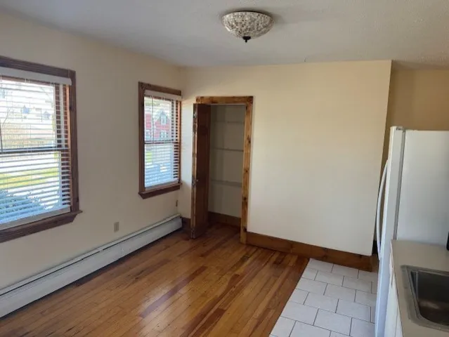 a view of an empty room with window and wooden floor