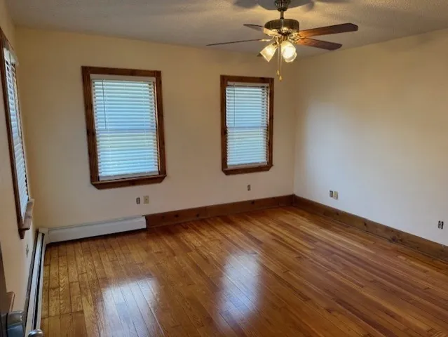 a view of an empty room with window and wooden floor
