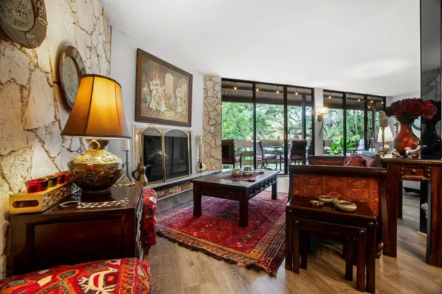 a living room with furniture a fireplace and floor to ceiling windows