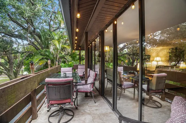 a view of a patio with a dining table and chairs with a barbeque grill and a potted plant