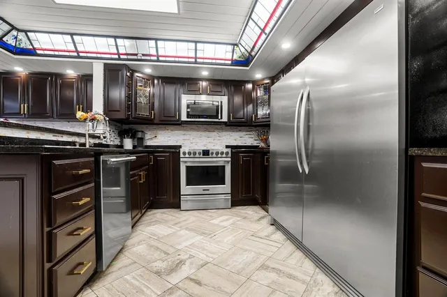 a kitchen with stainless steel appliances granite countertop a stove a refrigerator and a sink