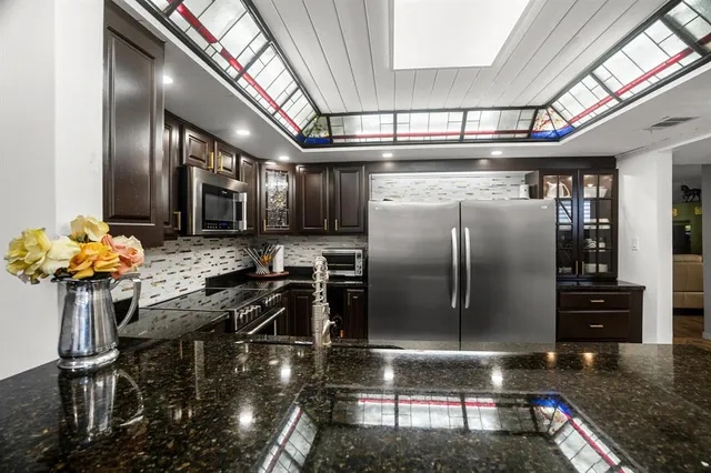 a kitchen with stainless steel appliances granite countertop a refrigerator a stove and a sink