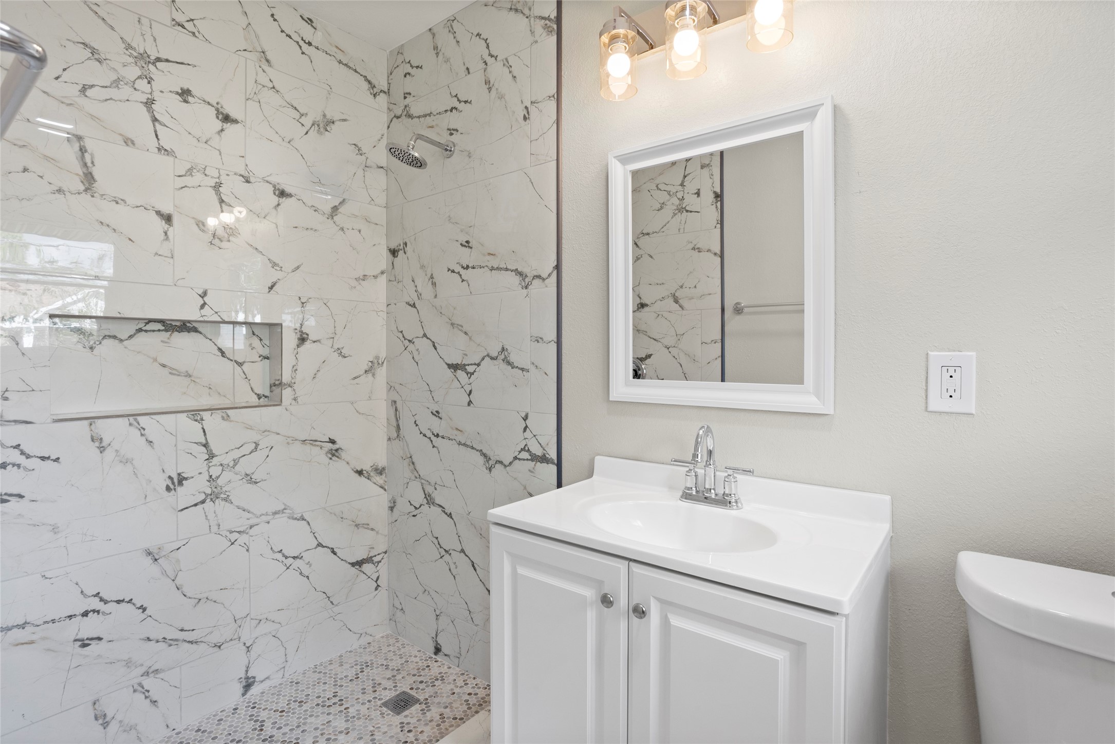 10127 Tolman Street Houston, TX 77034 - Photo 15 of 27 This primary bathroom features a sophisticated, modern design that emphasizes a clean aesthetic through high-contrast materials and updated fixtures.