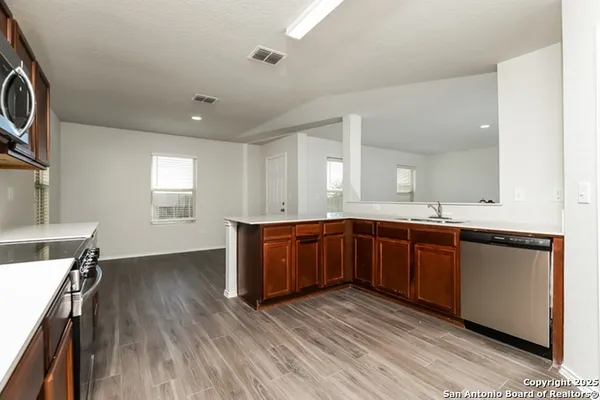 a kitchen with stainless steel appliances granite countertop a sink cabinets and wooden floor