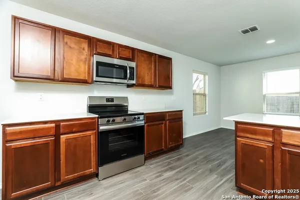 a kitchen with stainless steel appliances granite countertop wooden cabinets a stove top oven a sink and dishwasher