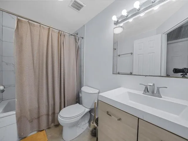 a bathroom with a sink a toilet a mirror and shower curtain