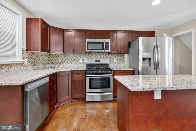 a kitchen with stainless steel appliances granite countertop a stove a sink and a refrigerator