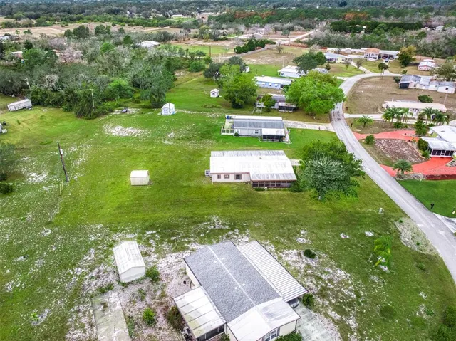 an aerial view of residential houses with outdoor space and trees
