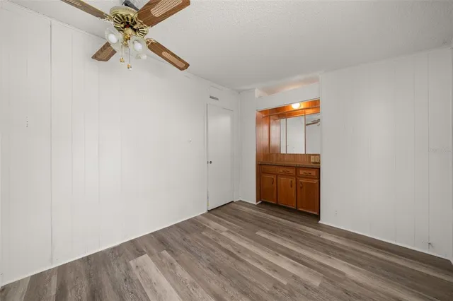 an empty room with a ceiling fan and wooden floor