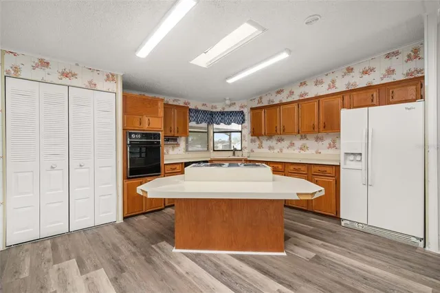 a large kitchen with kitchen island a stove a refrigerator a sink and dishwasher with wooden floor