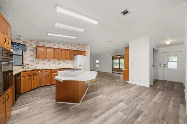 a large room with kitchen island a sink wooden floor and stainless steel appliances