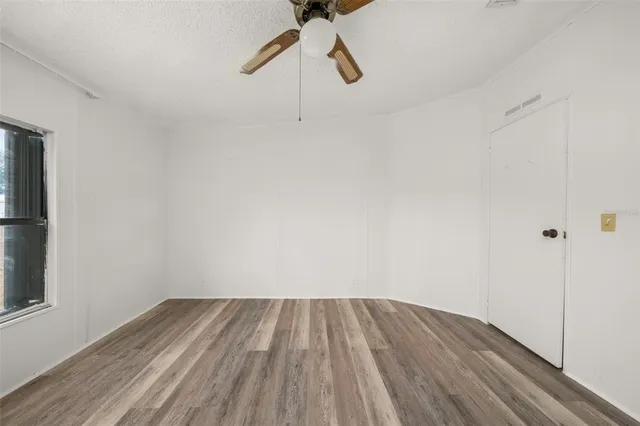 a view of a room with wooden floor ceiling fan and window
