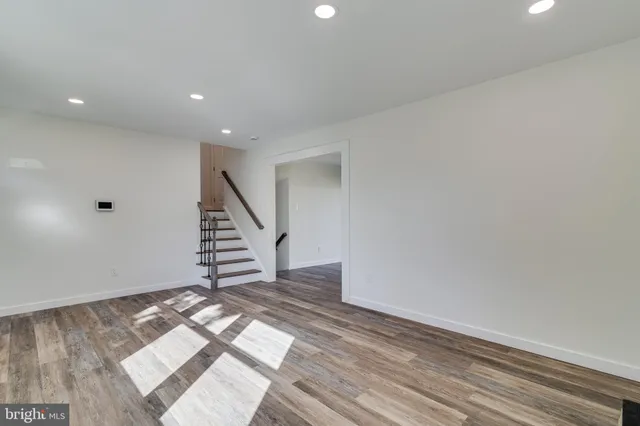 a view of an empty room with wooden floor fireplace and a window