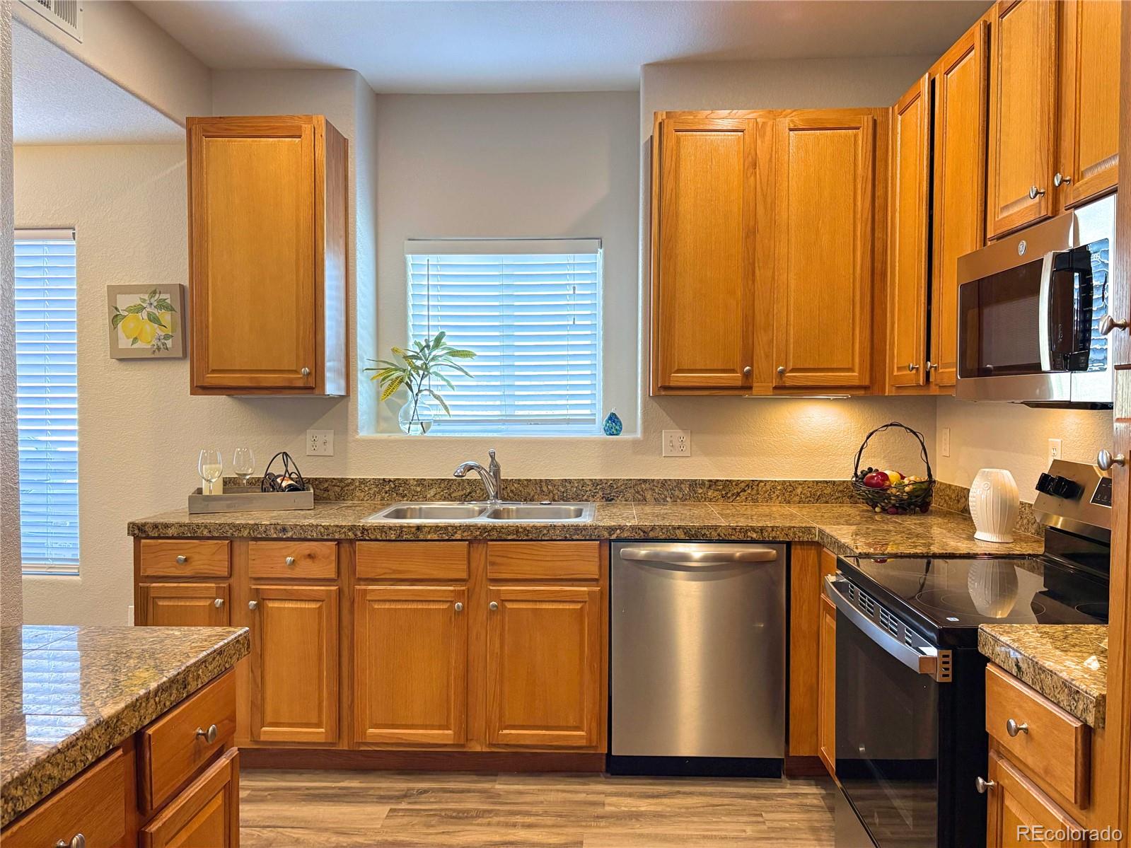 4608 Copeland Lane, Unit 101 Highlands Ranch, CO 80126 - Photo 6 of 16 a kitchen with stainless steel appliances granite countertop wooden cabinets a sink and a stove